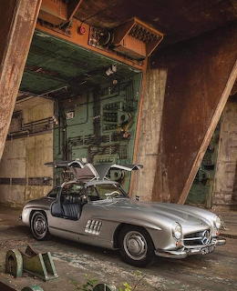 Silver classic Mercedes Gullwing car with doors raised in an old industrial warehouse