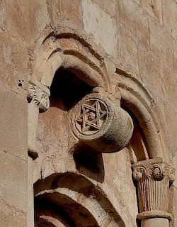 Romanesque stone carving with arched moldings and circular Star of David medallion on a column capital