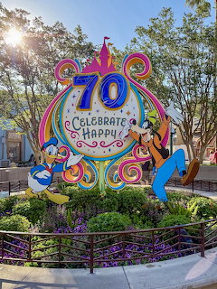 Vibrant Disneyland 70th anniversary celebration sign with Mickey Mouse, Minnie Mouse, and Goofy on rainbow decorated arch
