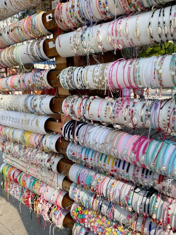 Rows of colorful beaded and seashell bracelets densely displayed on market racks