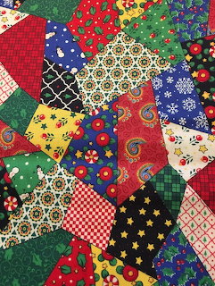 Colorful patchwork quilt with varied fabric patterns including florals, checks, and geometric designs