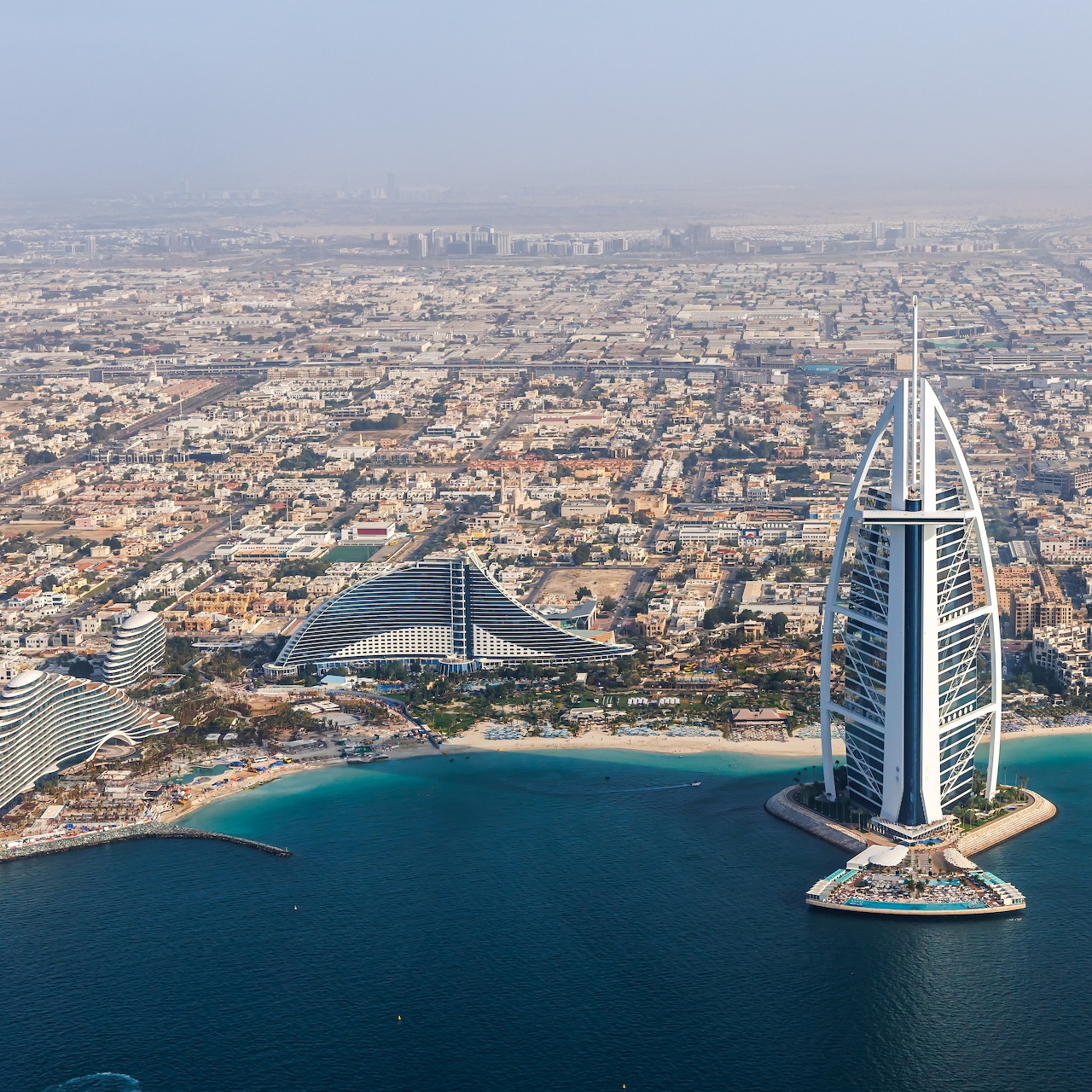 Aerial view of Dubai with the Burj Al Arab on the coast and the city spreading into the distance