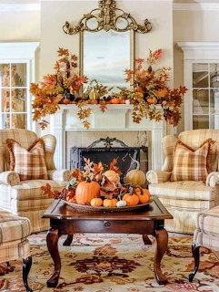 Cozy living room decorated for fall with pumpkins, autumn garland on fireplace mantel, and plaid upholstered chairs