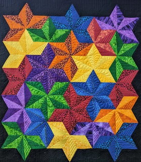 Colorful quilted textile with overlapping multicolored eight-pointed stars on dark blue background