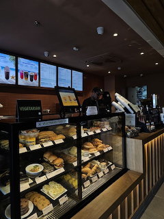 Starbucks cafe interior with pastry display cases and customer ordering at counter