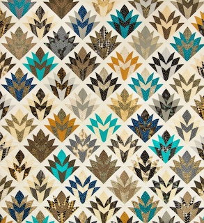 Cleopatra fan pattern quilt with teal, brown, and gold geometric blocks on cream fabric