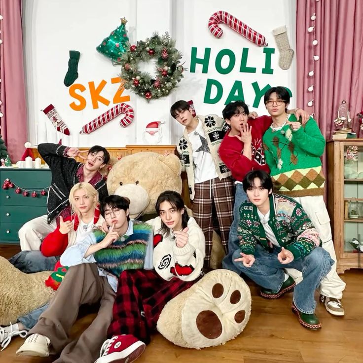 Eight people in holiday sweaters posing together in Christmas-decorated room with wreath and festive decorations