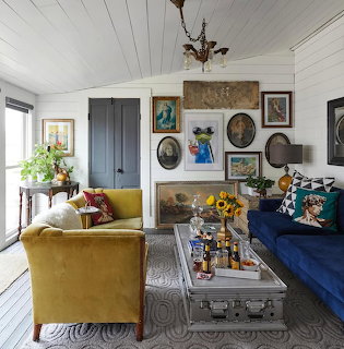 Cozy living room with yellow and blue sofas, decorative wall art, and rustic wooden coffee table