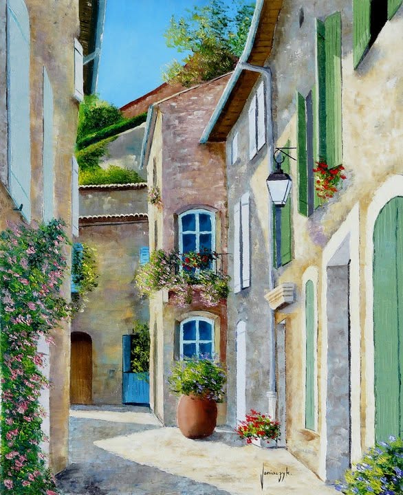 Sunny narrow street in a French Provençal village with pastel stone buildings and flower pots