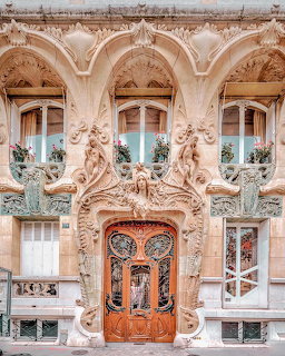 Ornate Art Nouveau facade with sculpted stonework, windows, and a decorative wooden door