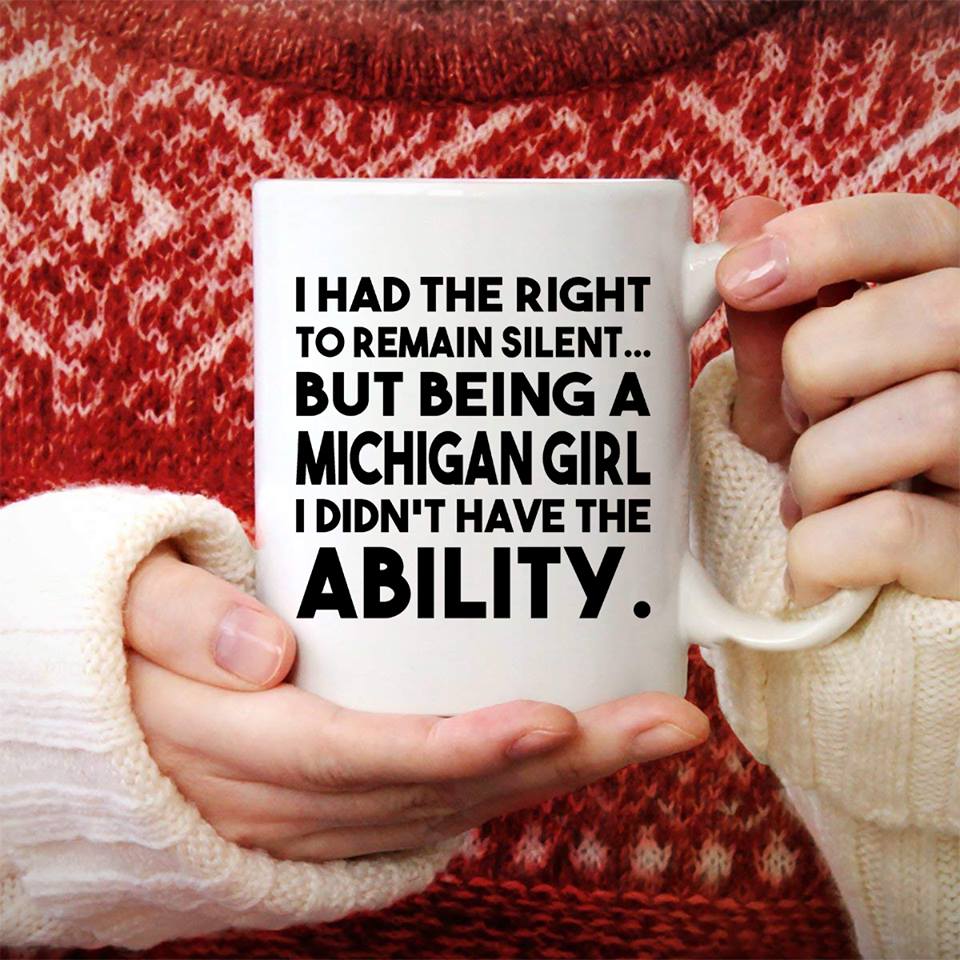 Hands holding a white mug with a Michigan quote in front of a red sweater