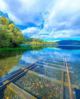 Submerged railway tracks visible through crystal clear lake water in Hokkaido Japan