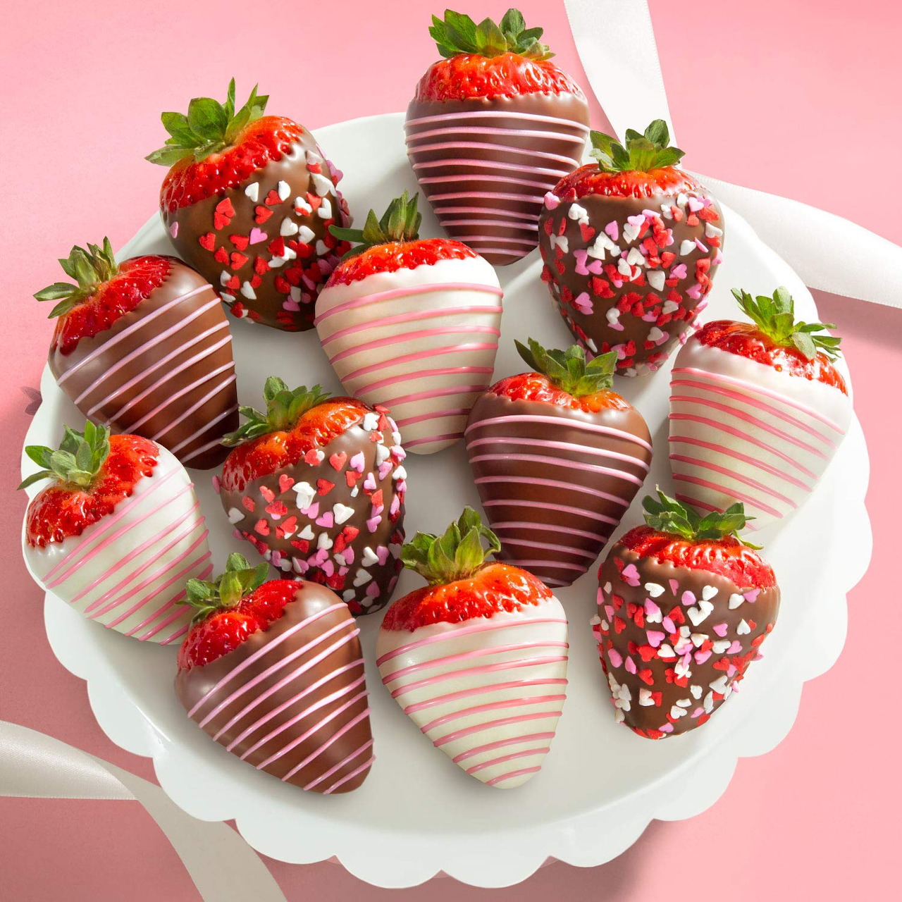 Chocolate-covered strawberries with drizzles and heart sprinkles on a white plate