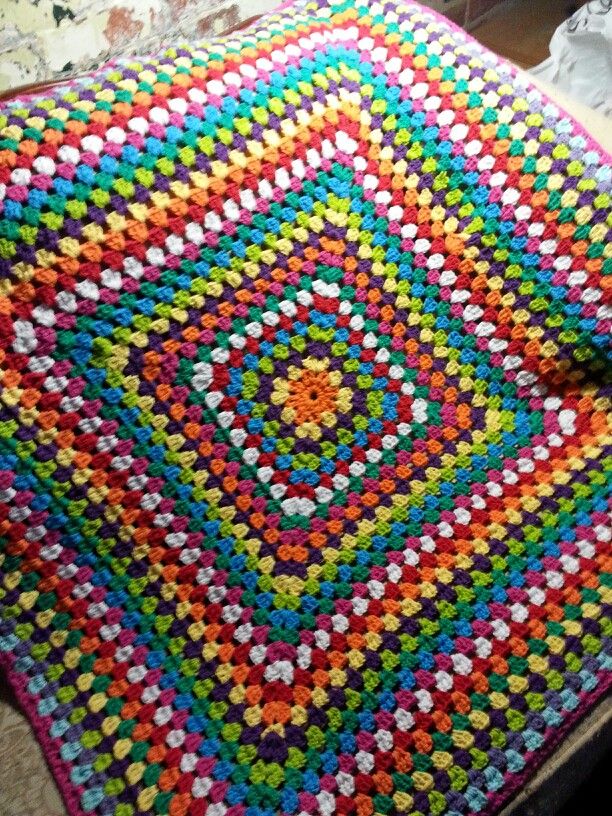 Colorful crocheted granny square blanket with concentric diamond pattern in rainbow colors