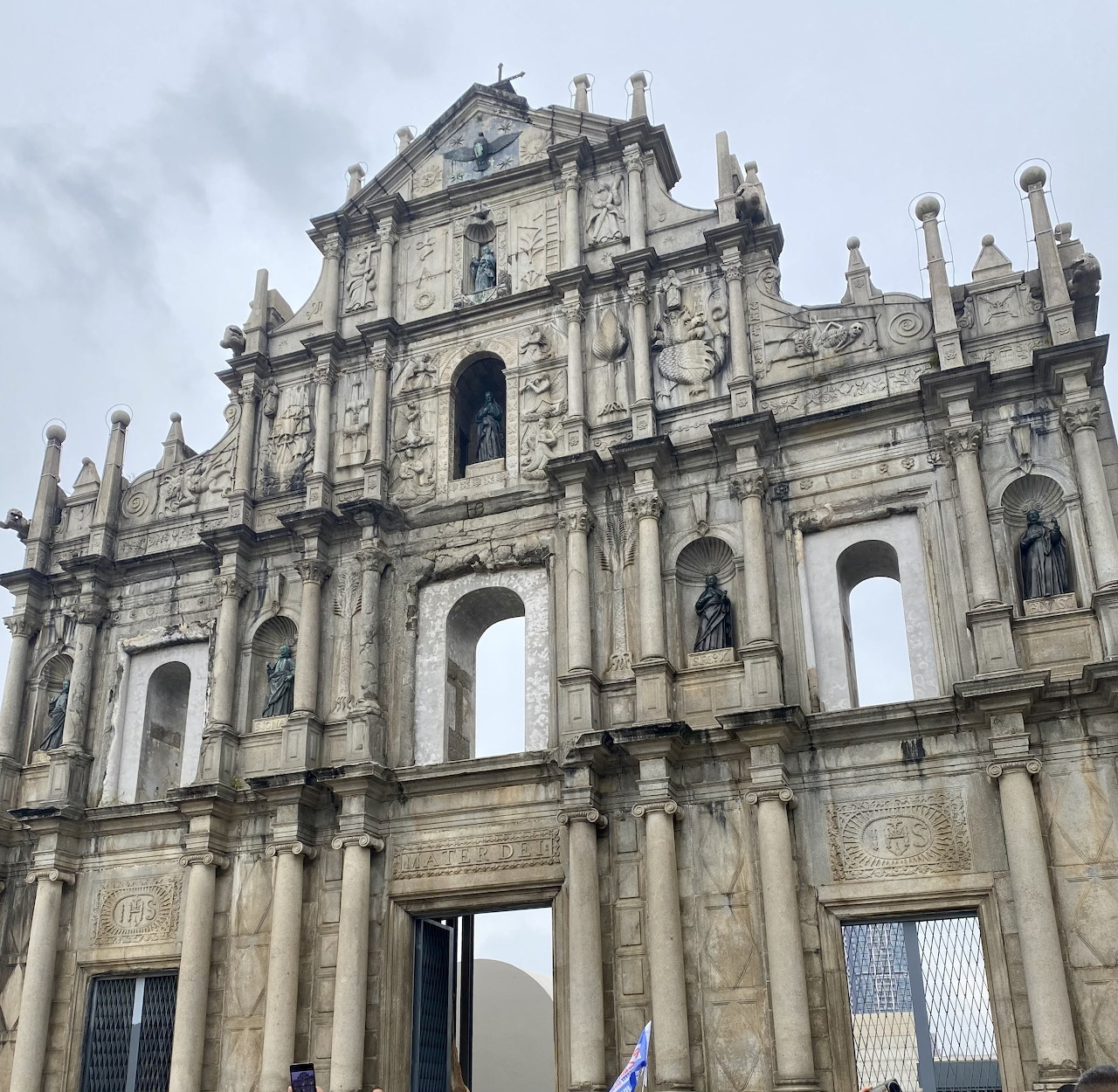 Stone ruins of St. Paul's facade in Macao with baroque carvings and arched openings against cloudy sky