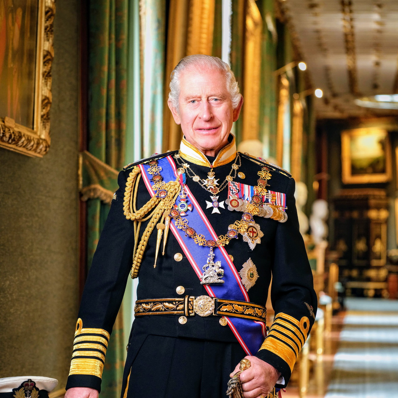 King Charles III standing in a palace corridor wearing a decorated military uniform