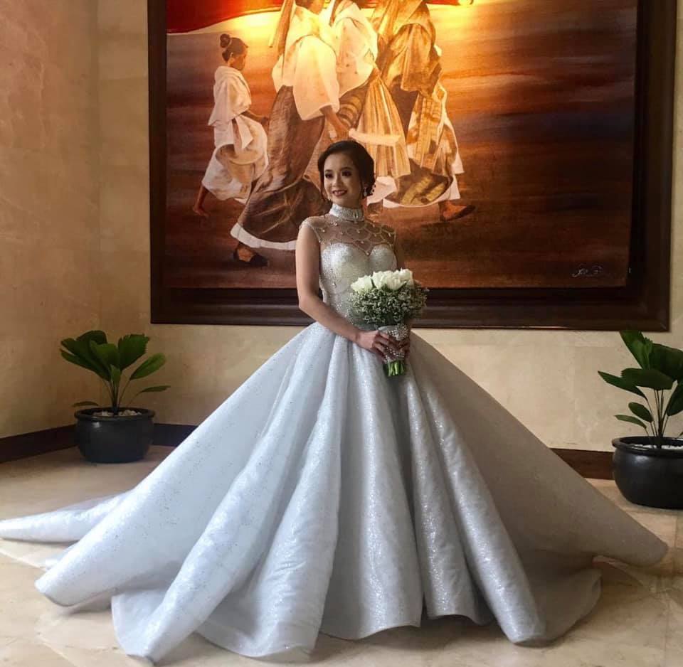 Bride in voluminous white ball gown holding bouquet indoors