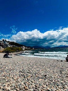 Rocky shoreline with dramatic clouds over lake and mountains in Bariloche, Argentina