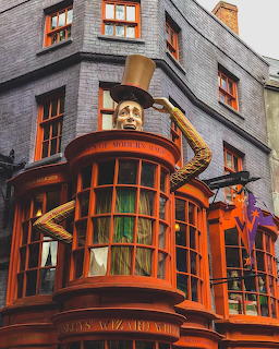 Weasleys Wizard Wheezes shop facade with a giant figure lifting a top hat above the orange building