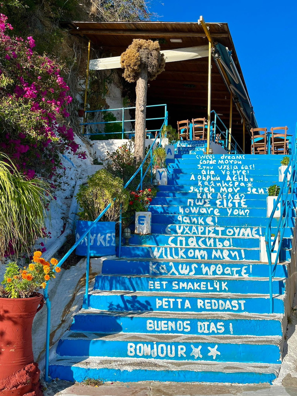 Bright blue staircase with multilingual welcome messages painted on steps, Agia Galini, Crete, Greece