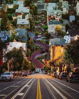 San Francisco steep street leading down to the winding curves of Lombard Street with houses and gardens