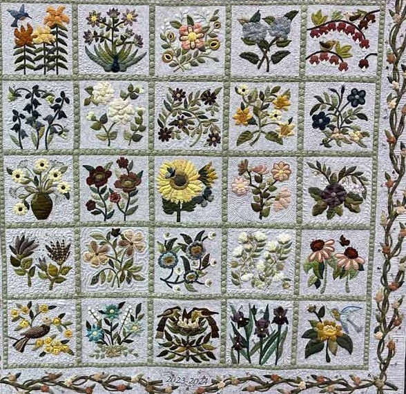 Square patchwork quilt with floral and bird blocks in a grid and a patterned border