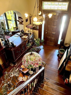 Overhead view of an antique foyer with staircase, wooden floor, sideboard, and stained glass lamp