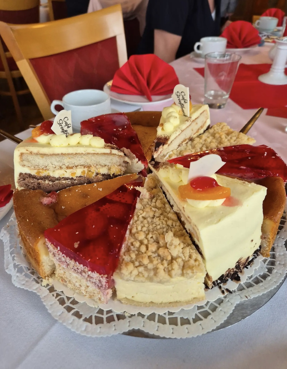 Circular platter with six different cake slice varieties arranged around a red folded napkin in the center