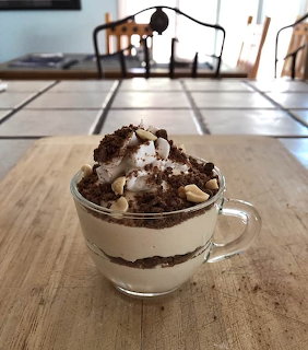 Layered chocolate peanut butter dessert in clear glass mug topped with whipped cream and chocolate crumbles