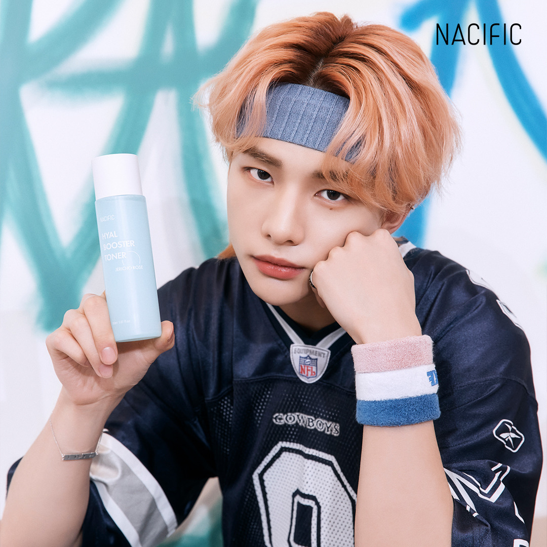 Young man with pink hair in a jersey and headband holding a light blue bottle