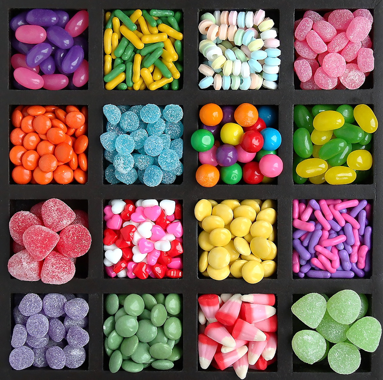 Grid of colorful candies in black compartments showing gummies, jellies and sweets in various shapes and colors