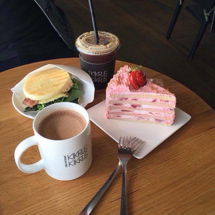 Cafe table with coffee drinks, pink layered cake, and sandwich