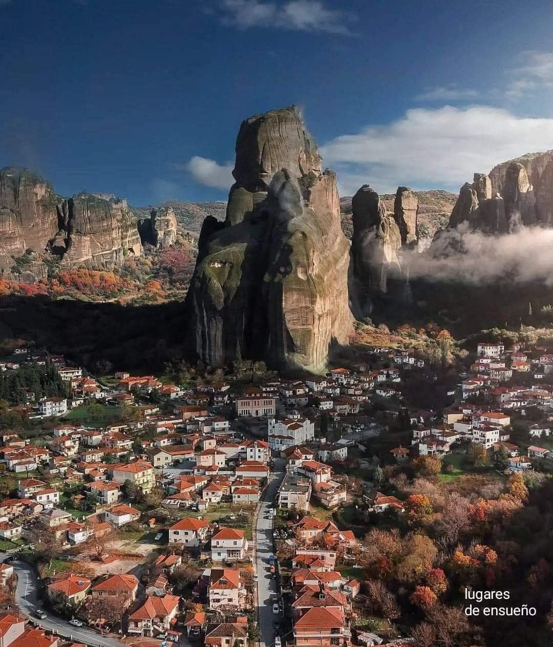 Aerial view of Kalambaka town with massive Meteora rock pillars rising above red-roofed buildings, Greece.