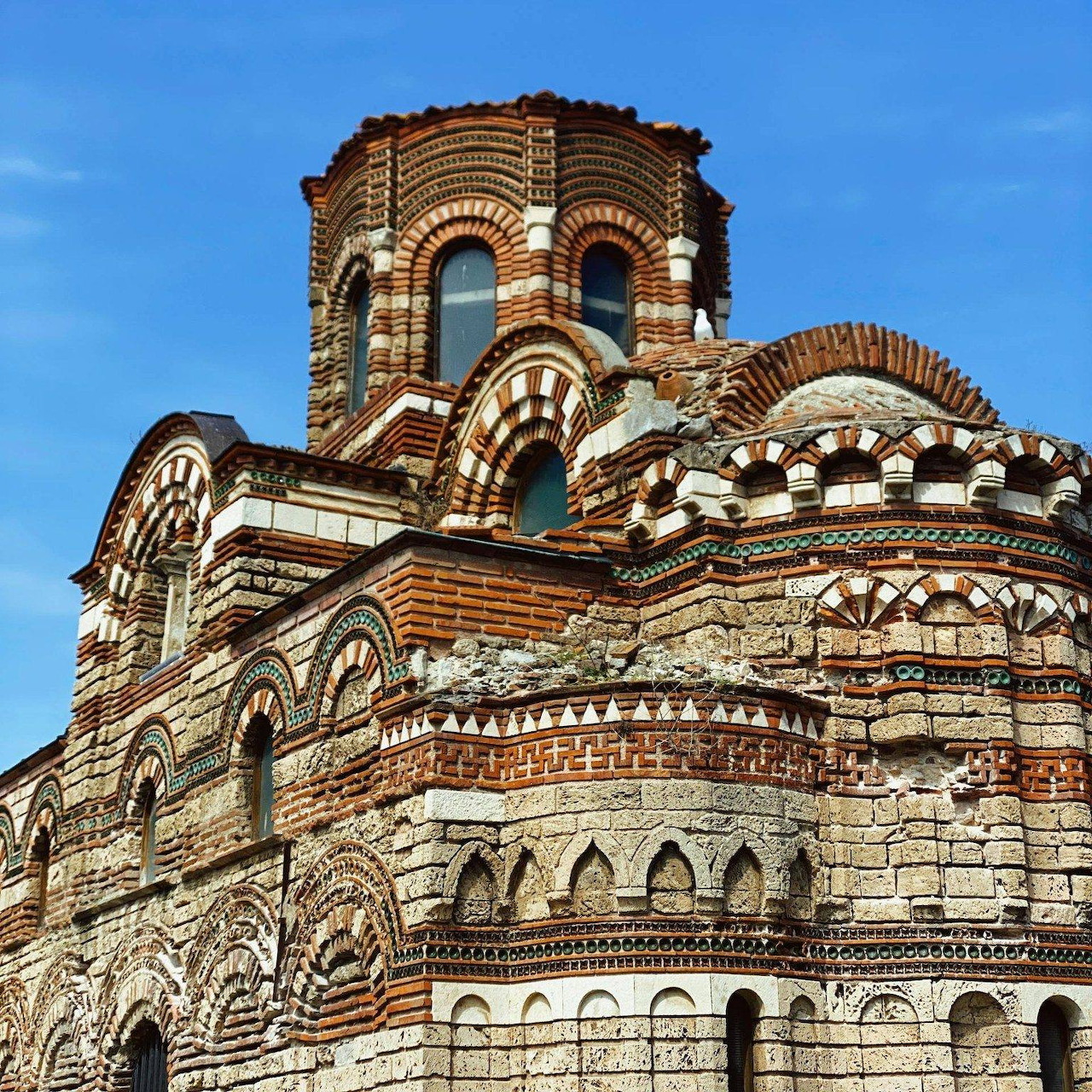 Ornate historic church facade with striped brickwork and arches under a blue sky