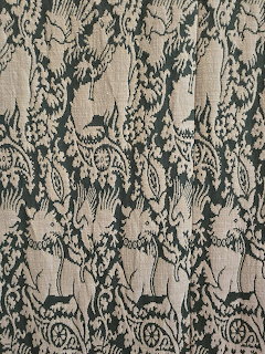 Close-up of vintage tapestry fabric with repeating woven figures and ornate floral pattern