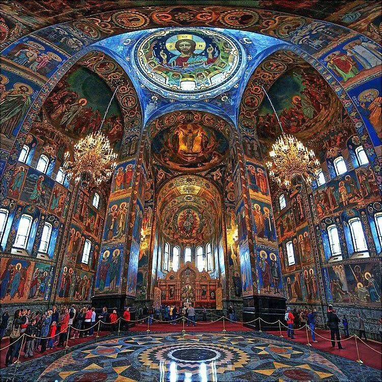 Richly decorated Orthodox church interior with colorful religious frescoes covering domed ceiling and walls