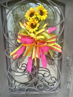 Sunflower wreath with yellow and pink ribbons hanging on decorative iron door