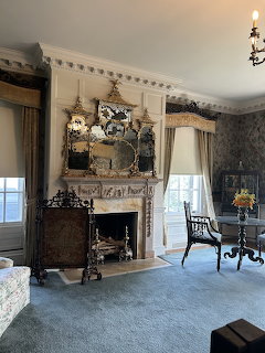 Formal sitting room with carved fireplace, large mirror, candelabra and antique chairs