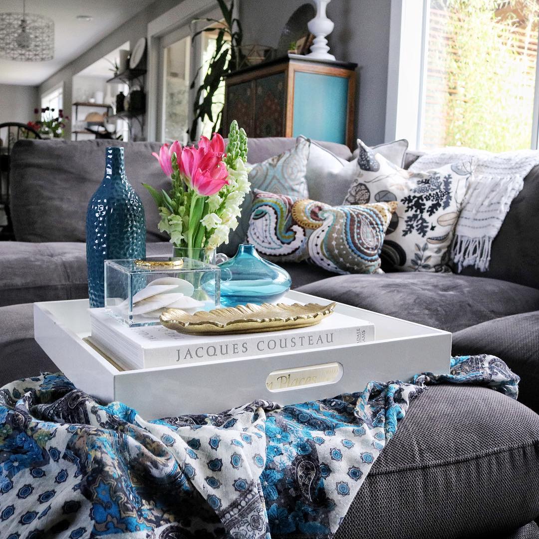 Modern living room with gray sofa, white coffee table, pink flowers, and turquoise decor accents