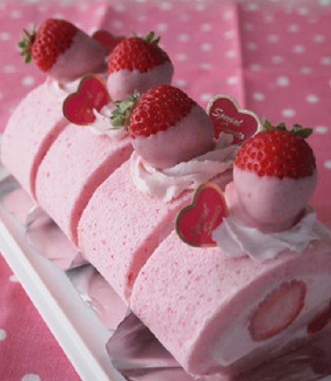 Pink strawberry Swiss roll cake topped with fresh strawberries and cream on a white tray
