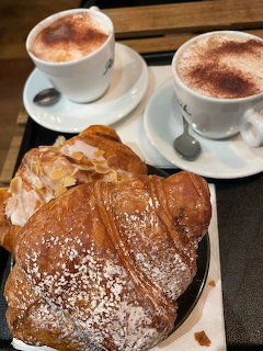 Two cups of coffee with croissants and pastries on a tray