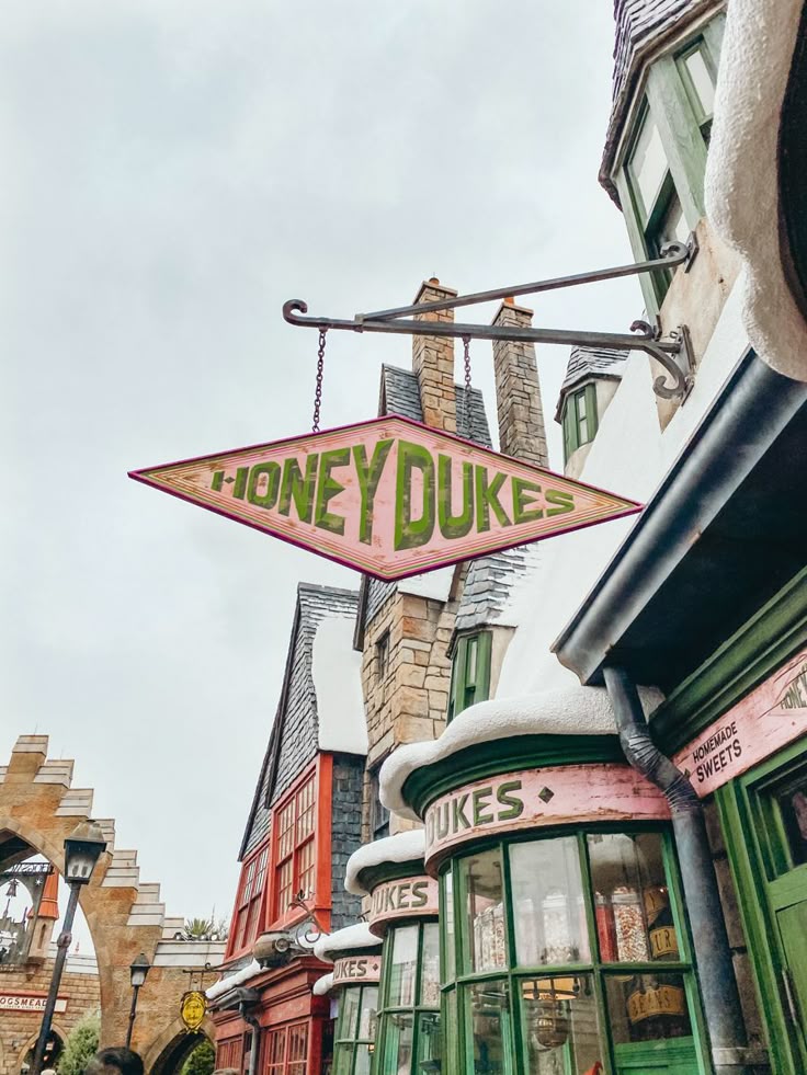 Pink Honeydukes sign hanging above a colorful shopfront on a themed village street