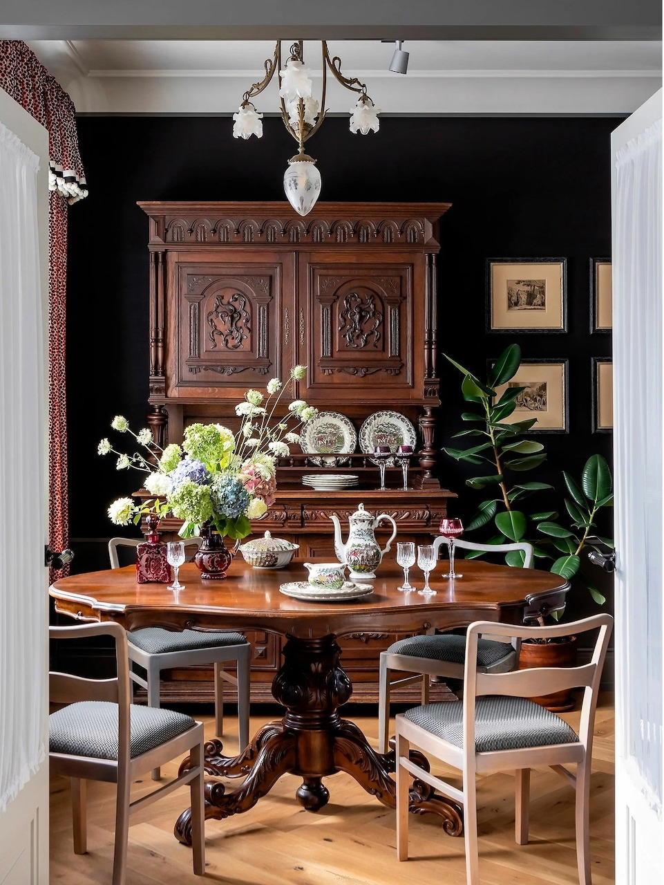 Traditional dining room with dark wood cabinet, round table, chairs, and flower arrangement