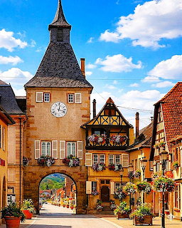Medieval clock tower with half-timbered facade and archway in a picturesque Alsatian village street