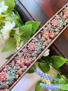 Colorful embroidered floral ribbon on wooden boxes with white and purple flowers and green leaves