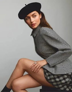 Woman in black beret and checkered blazer seated in elegant pose