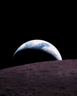 Earth rising over the grey lunar horizon against the darkness of space