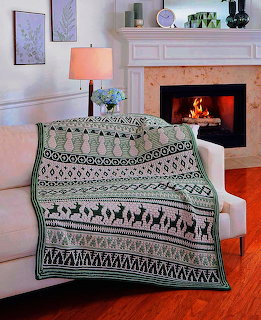 Green and white reindeer patterned throw blanket on white armchair near fireplace in living room