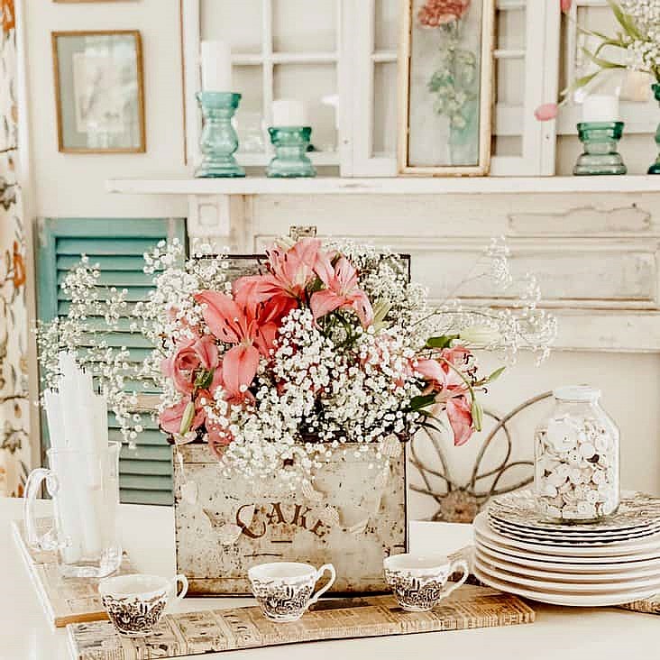Pink lilies and white baby's breath in a rustic container on a decorated table indoors