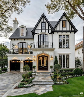 White Tudor-style house with black half-timbering, arched entry, balcony, and landscaped front yard